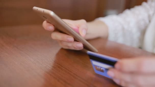 Mujer hace una compra usando un teléfono inteligente y una tarjeta bancaria . — Vídeos de Stock