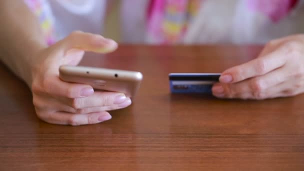 Vrouw maakt een aankoop via een smartphone en een bankkaart. — Stockvideo