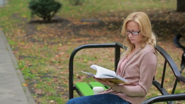 Szőke nő olvasókönyv a fogorvostudomány őszi parkban. — Stock videók