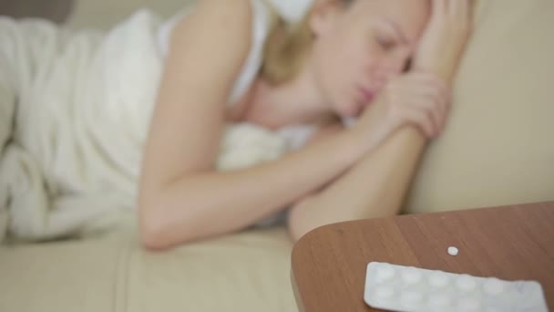 Zieke vrouw liggend op het bed. pillen en glas water. Drink tabletten. pijnstiller — Stockvideo