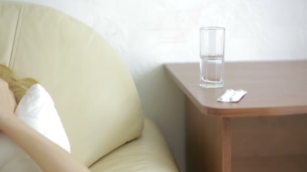 Zieke vrouw liggend op het bed. pillen en glas water. Drink tabletten. pijnstiller — Stockvideo