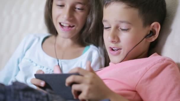 Adolescentes usando smartphone con auriculares. hermano y hermana con un teléfono — Vídeo de stock
