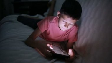 Genç çocuk bir cep telefonu veya bir yatakta smartphone ile oynamak. gece