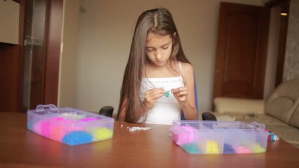 Niña teje pulsera de bandas elásticas. Bandas de goma de colores para tejer — Vídeos de Stock