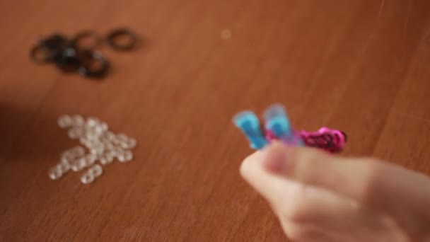 Niña teje pulsera de bandas elásticas. Bandas de goma de colores para tejer — Vídeos de Stock