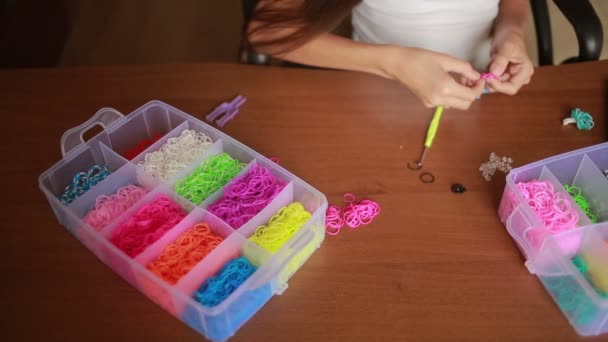 Meisje weven armband van elastiekjes. Gekleurde elastiekjes voor het weven — Stockvideo