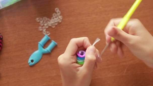 Niña teje pulsera de bandas elásticas. Bandas de goma de colores para tejer — Vídeo de stock