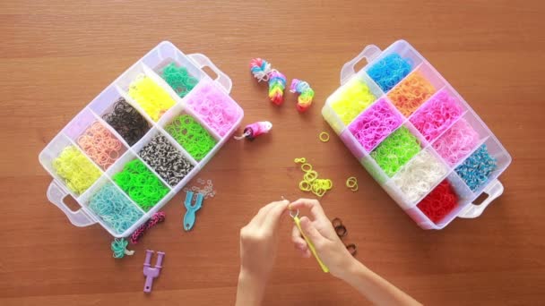 Menina tecer pulseira de elásticos. Faixas de borracha coloridas para tecelagem — Vídeo de Stock