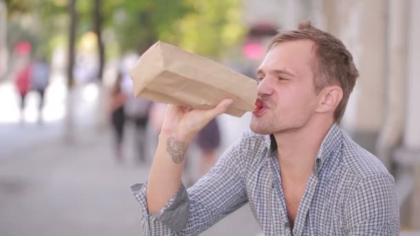 Slarvig man dricka alkohol på gatan. öl i en papperspåse. — Stockvideo