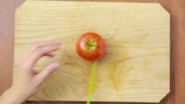 Γυναίκα κόβει μια ντομάτα σε ένα ξύλινο ταμπλό. θέα από ψηλά. το Top view — Αρχείο Βίντεο