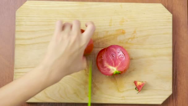 Vrouw snijdt een tomaat op een houten bord. Bekijk van bovenaf. bovenaanzicht — Stockvideo