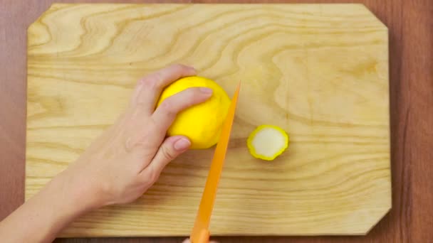 Женщина режет лимон на деревянной доске. Вид сверху. вид сверху — стоковое видео