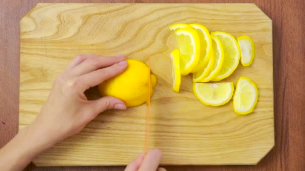 Kadın bir ahşap tahta üzerine limon keser. Yukarıdan görüntüleyin. Üstten Görünüm — Stok video