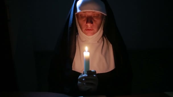 Жінка черниця молиться вночі. палаючі свічки. Жінка в одязі черниці — стокове відео