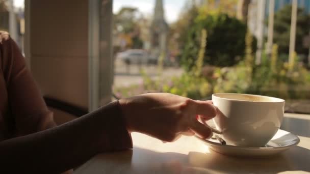 Femme mélangeant la mousse du café et la mangeant. fermer les tasses — Video