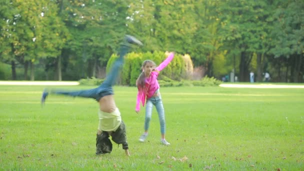 Çocuk takla yapıyor. Çocuk açık havada oyun. kız ve erkek kardeşim akrobatlar. — Stok video