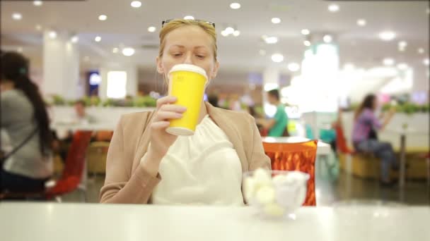 Vrouw in een supermarkt drinken koffie. kauwen van voedsel — Stockvideo