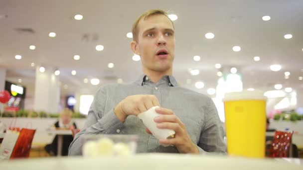 Jovem a beber um café no café. comer batatas fritas — Vídeo de Stock