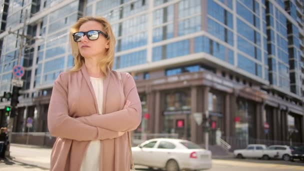Mujer con gafas de sol de pie en una calle concurrida. mujer, residente de la ciudad . — Vídeo de stock