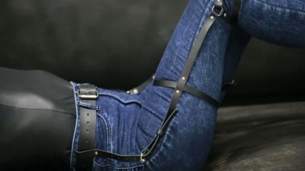 Девушка в джинсах с кожаной подвязкой новые модные тенденции. ремни на бедрах — стоковое видео