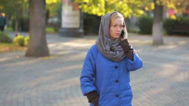Sonbahar parkta cep telefonuyla konuşan genç gülümseyen kadın.