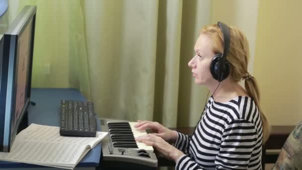 Žena píše hudbu na počítači. Digitální piano midi klávesnice — Stock video