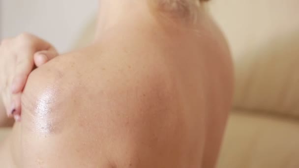 Девушка массирует кремовое плечо. боль в суставах косметические процедуры — стоковое видео
