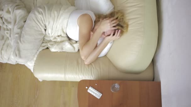 Больная женщина лежит на кровати. таблетки и стакан воды. пить таблетки. painkiller — стоковое видео