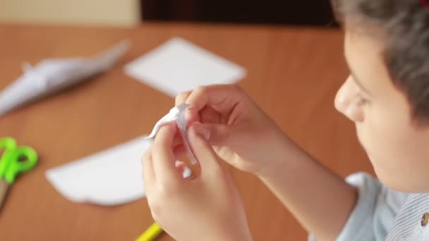 Маленький мальчик рисует на бумажном оригами. Хобби-крафты — стоковое видео