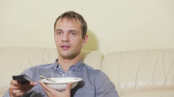 Homme avec télécommande regardant la télévision à la maison — Video