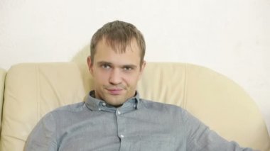 Uzaktan kumandalı bir adam evde televizyon izliyor.