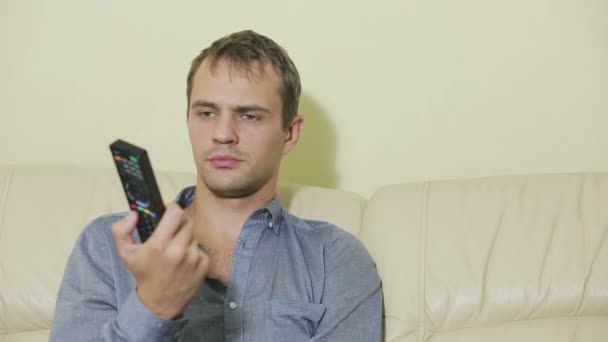 Homme avec télécommande regardant la télévision à la maison — Video