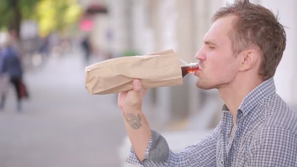 Slordig man drinken van alcohol in de straat. bier in een papieren zak. — Stockvideo