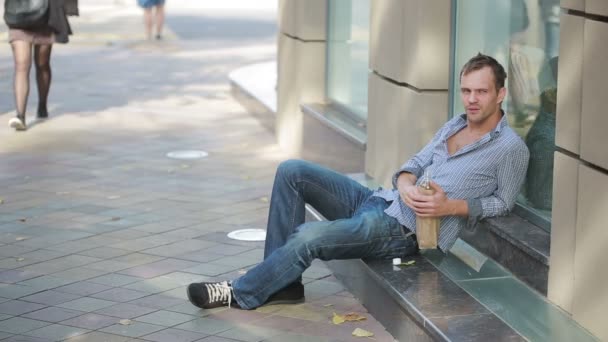 Drunk man lying on the pavement outside. man drinking beer from a paper bag — Stock Video