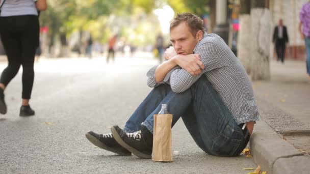 Drunk hangover man lying on the pavement. man drinking beer from paper bag. — Stock Video