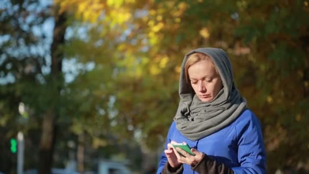 Jeune femme souriante parlant sur un téléphone portable dans le parc d'automne . — Video