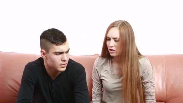 Красива молода пара конфліктує, сидячи на дивані сперечаються нещасливі — стокове відео