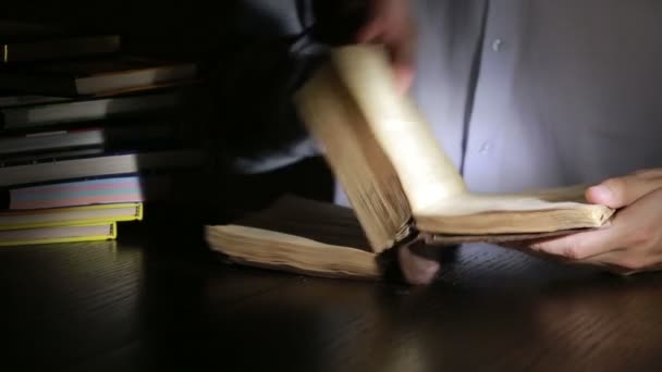 Slimme man laat in de nacht studeren, hij zit aan Bureau- en leesboek — Stockvideo