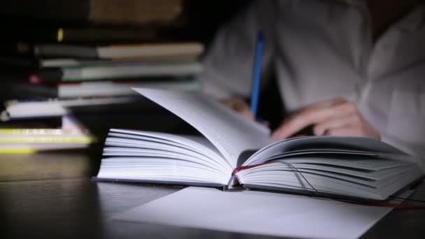 Homem inteligente estudando tarde da noite, ele está sentado na mesa e lendo livro — Vídeo de Stock