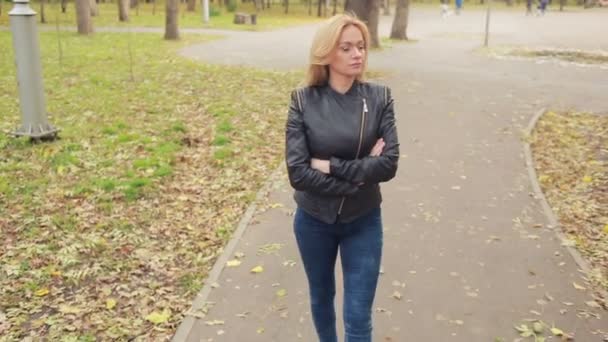 Schöne junge Frau im Herbst Park. Blondine in Lederjacke — Stockvideo
