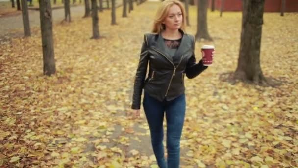 Mooie jonge vrouw in herfst park. blonde in een leren jas — Stockvideo
