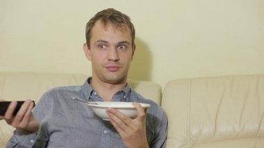 Uzaktan kumandalı bir adam evde televizyon izliyor.