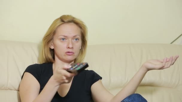 Mujer joven viendo la televisión en casa. chica aburrida con control remoto — Vídeo de stock