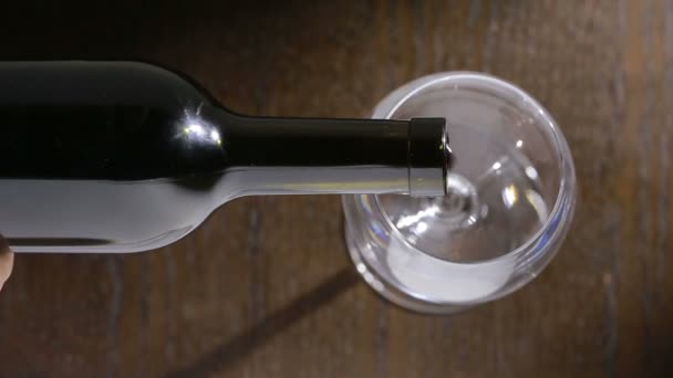 Gieten van rode wijn in het glas tegen houten achtergrond. bovenaanzicht — Stockvideo