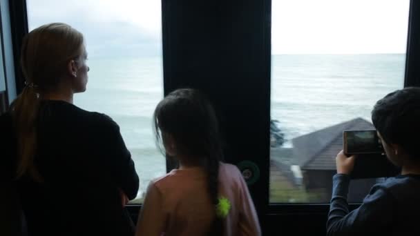 Family traveling on a train and looks through the window at the sea — Stock Video