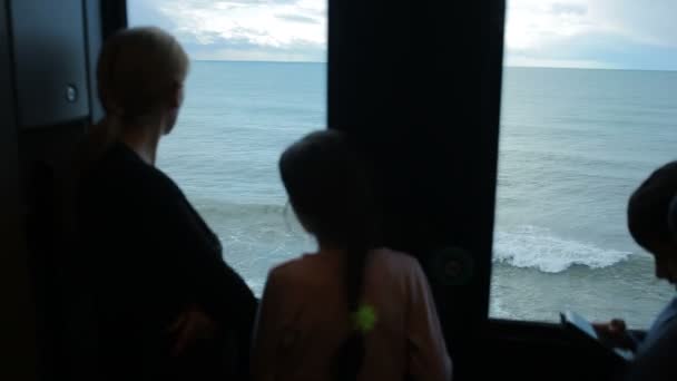 Familia viajando en un tren y mira a través de la ventana al mar — Vídeos de Stock