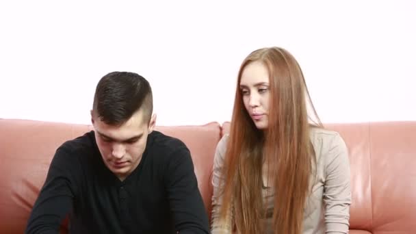 Hermosa joven pareja conflicto sentado en un sofá discutir infeliz — Vídeos de Stock