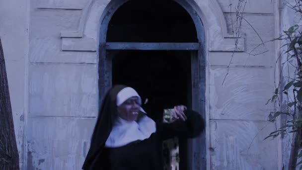 Monja zombi. Mujer diabólica disfrazada de monja caminando por el templo. Halloween. — Vídeos de Stock