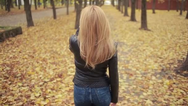 Bella giovane donna nel parco autunnale. bionda in giacca di pelle — Video Stock