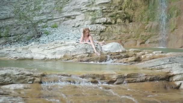Сексуальная девушка в бикини принимает душ в водопаде — стоковое видео